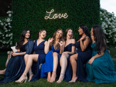 bridesmaids laugh on a couch under a love sign