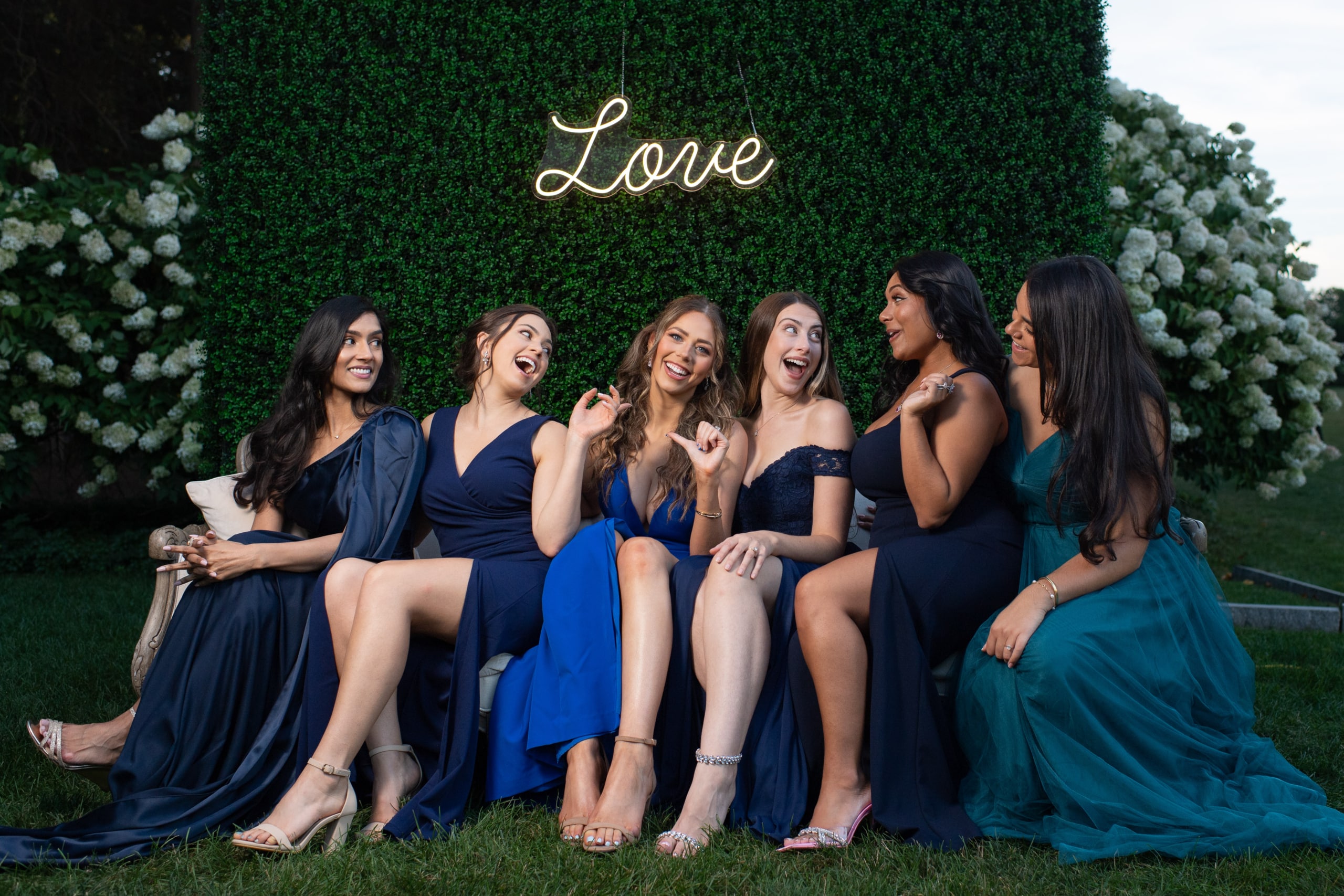 bridesmaids laugh on a couch under a love sign