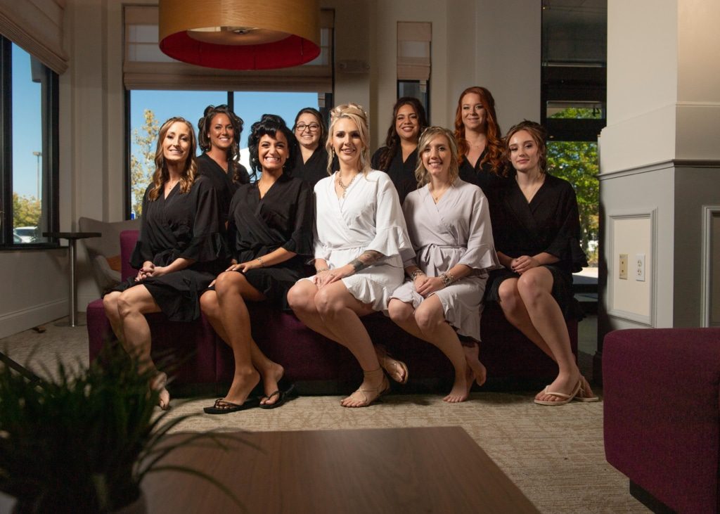 a bride surrounded by her bridesmaids pose in robes before the wedding