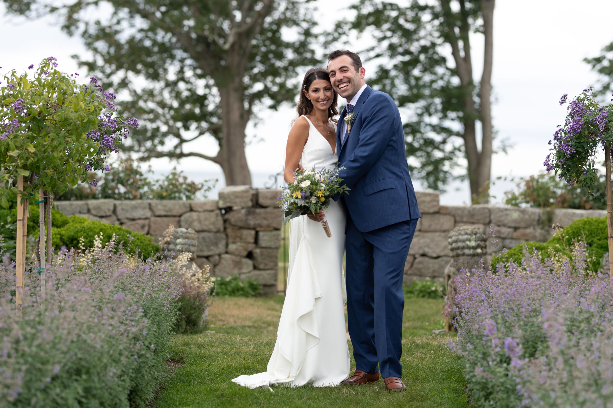 A bride and groom pose together in the garden