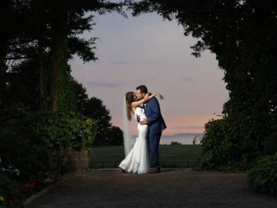 a bride and groom kiss while the sun sets behind them