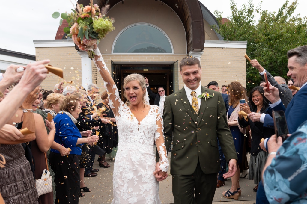 bride and groom exit church as guests toss flower petals